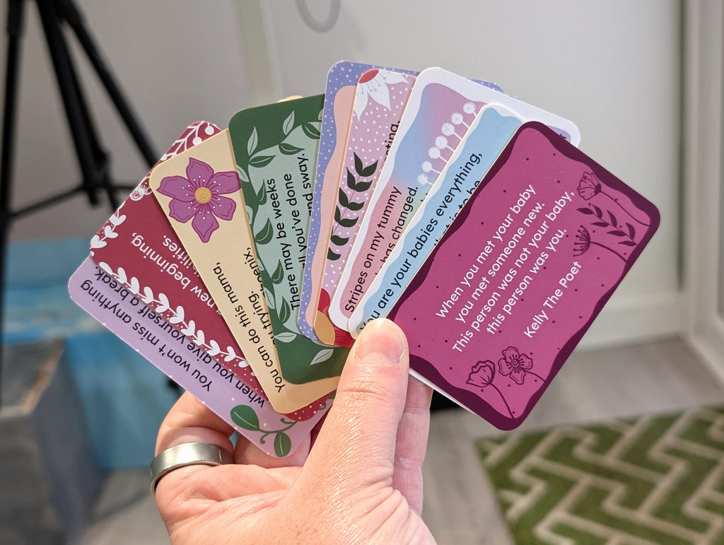 Hand holding a set of colorful cards with text and designs for new mums 
