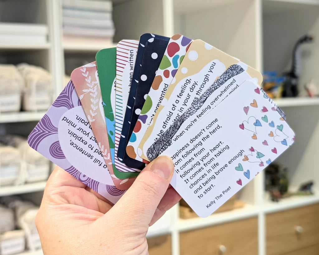 Hand holding a stack of colorful cards with text and patterns.