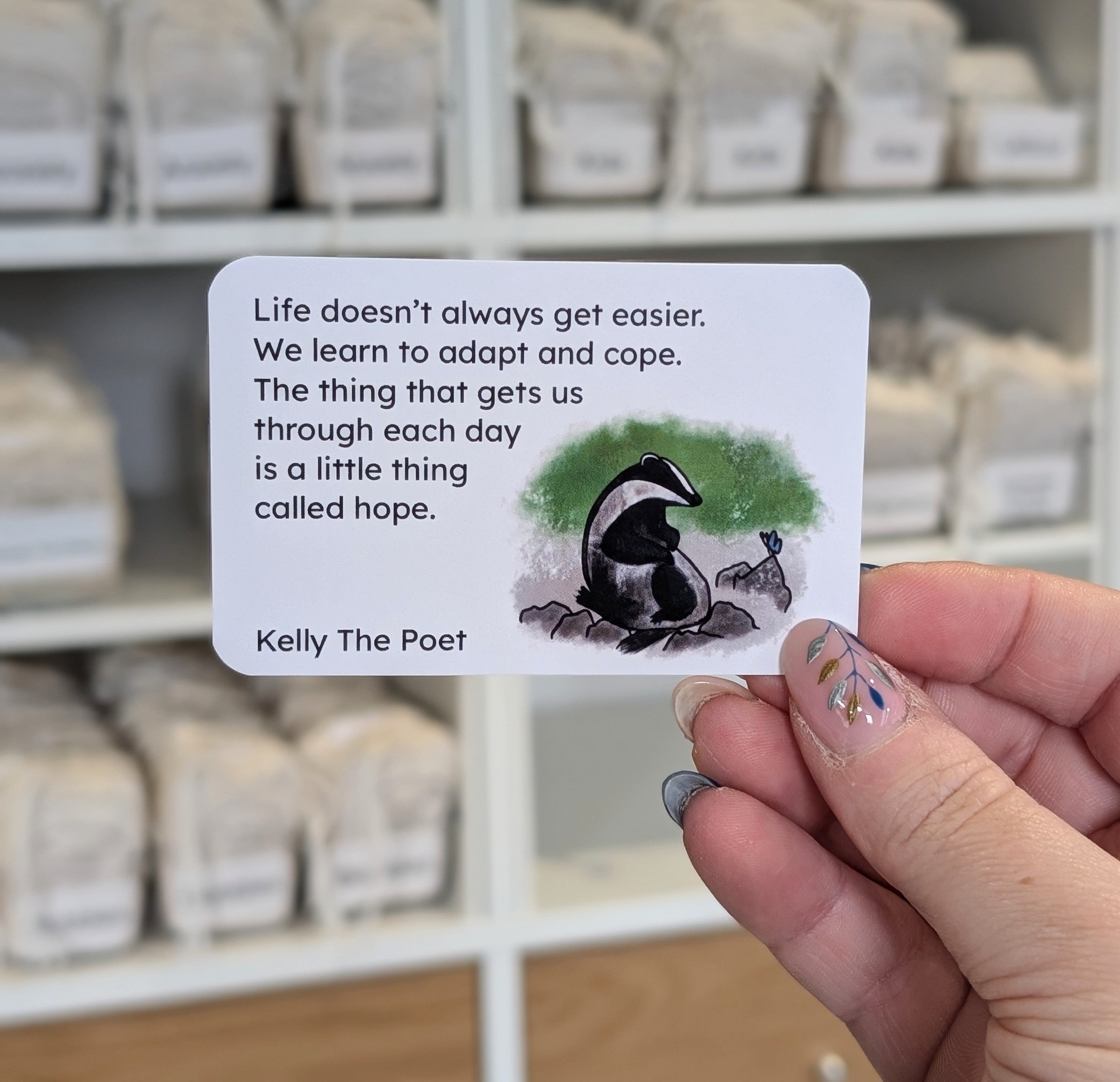 Card with a quote about hope held by a hand in front of shelves.